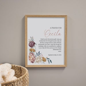 May include: A framed print with a floral design and a prayer for Cecila. The text reads "A Prayer for Cecila. I thank you for this precious gift. I pray you would protect her through the years. May she become a young woman of great character, seeking after your heart. I pray that through the challenges of life, she would find her confidence in you. May she know your joy as her strength (Nehemiah 8:10). Amen. Baptized on May 19, 2024."