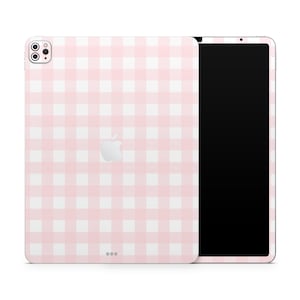 Pode incluir: Uma capa para iPad com padrão xadrez rosa e branco com uma tela preta. A capa tem um recorte para a câmera e um logotipo da Apple branco.