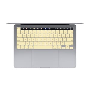 May include: A silver laptop computer with a light yellow keyboard cover. The keyboard has standard keys, including function keys, number keys, and arrow keys.