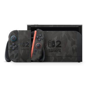 以下が含まれることがあります： 迷彩柄のNintendo Switchコンソール。コンソールには、青いアクセントとオレンジ色のアクセントが付いた2つの取り外し可能なコントローラーがあります。コンソールとコントローラーには、Nintendo Switchのロゴと数字の2が表示されています。