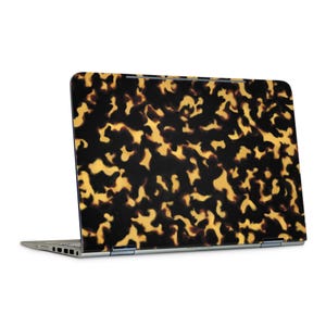 May include: A laptop with a tortoiseshell pattern on the lid. The pattern features a mix of dark brown and golden yellow shapes, creating a unique and stylish design. The laptop is open, revealing the screen and keyboard.