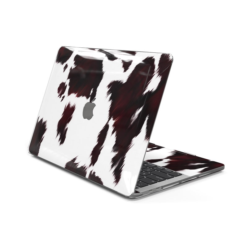 May include: A laptop computer with a white and black cowhide pattern on the lid and keyboard. The laptop is closed and the lid is facing the camera.