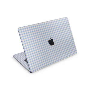 May include: A laptop with a light blue and white gingham pattern on the lid and keyboard area. The Apple logo is visible on the lid. The laptop is open, displaying the keyboard and screen.
