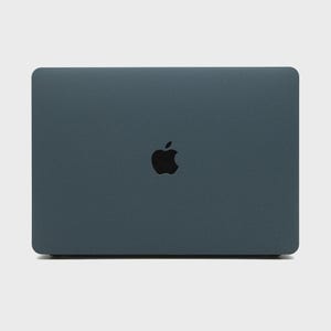 May include: A closed, dark teal laptop with rounded corners. The Apple logo is centered on the lid in black. The laptop is set against a plain, light background.