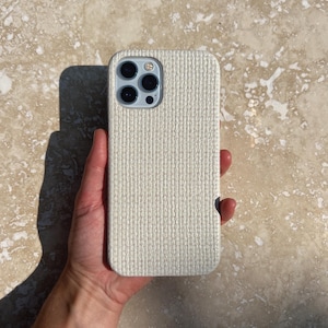 May include: A white woven phone case for an iPhone.
