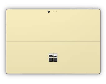 May include: A pale yellow tablet computer with a black Microsoft logo on the back.