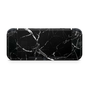 Puede incluir: Consola Nintendo Switch negra con una piel de patrón de mármol blanco.
