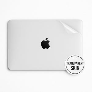 May include: A white laptop with a black Apple logo and a clear protective skin with the text "TRANSPARENT SKIN" on a white background.