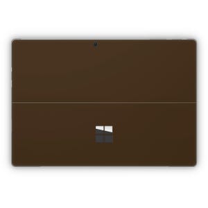 May include: A dark brown tablet computer with a silver frame and a white Microsoft logo on the back.