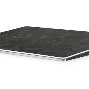 May include: A black wireless mouse with a camouflage pattern on the top. The mouse has a silver trim around the edges.