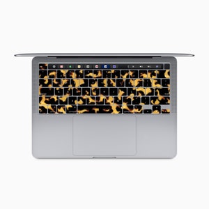 May include: A silver laptop computer with a keyboard covered in a brown and gold tortoise shell pattern.