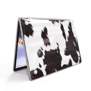 May include: A clear plastic laptop case with a black and white cow print design. The case is designed to fit a laptop computer.