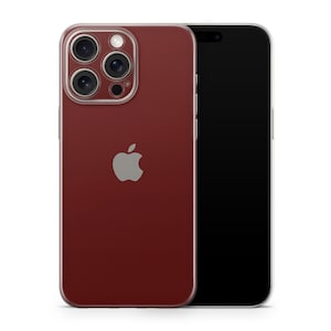 Puede incluir: Un smartphone rojo con una funda protectora transparente. El teléfono tiene un logotipo de Apple plateado y una cámara con varias lentes. La pantalla de un segundo smartphone negro es visible a la derecha.