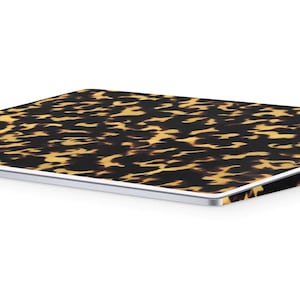 May include: A wireless trackpad with a tortoiseshell pattern. The trackpad is white and has a slightly angled design.