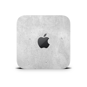 May include: A square, grey, textured, concrete-like sticker with a black Apple logo in the centre.