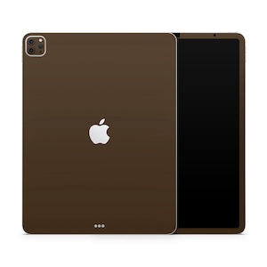 Peut inclure: Une coque pour iPad Pro de couleur marron avec un logo Apple blanc. La coque est fermée et l'écran est tourné vers l'extérieur.