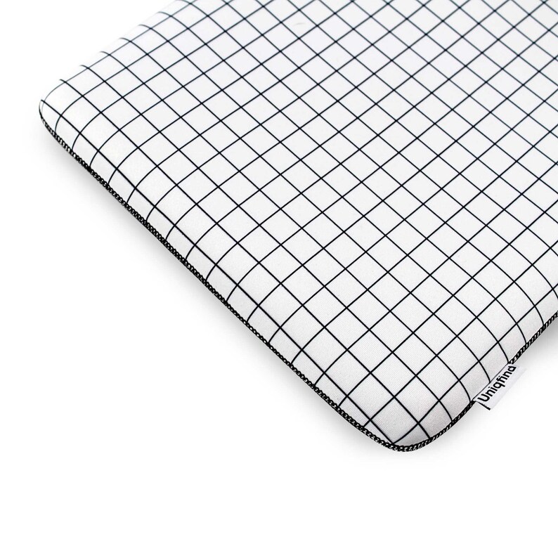 Puede incluir: Funda para port&aacute;til blanca con un patr&oacute;n de cuadr&iacute;cula negra y un logotipo negro de Uniqfind en la esquina inferior derecha.