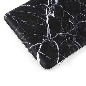Puede incluir: Funda para port&aacute;til negra con un patr&oacute;n de m&aacute;rmol blanco. La funda tiene una cremallera y una etiqueta blanca "Uniqfind" en la esquina inferior derecha.