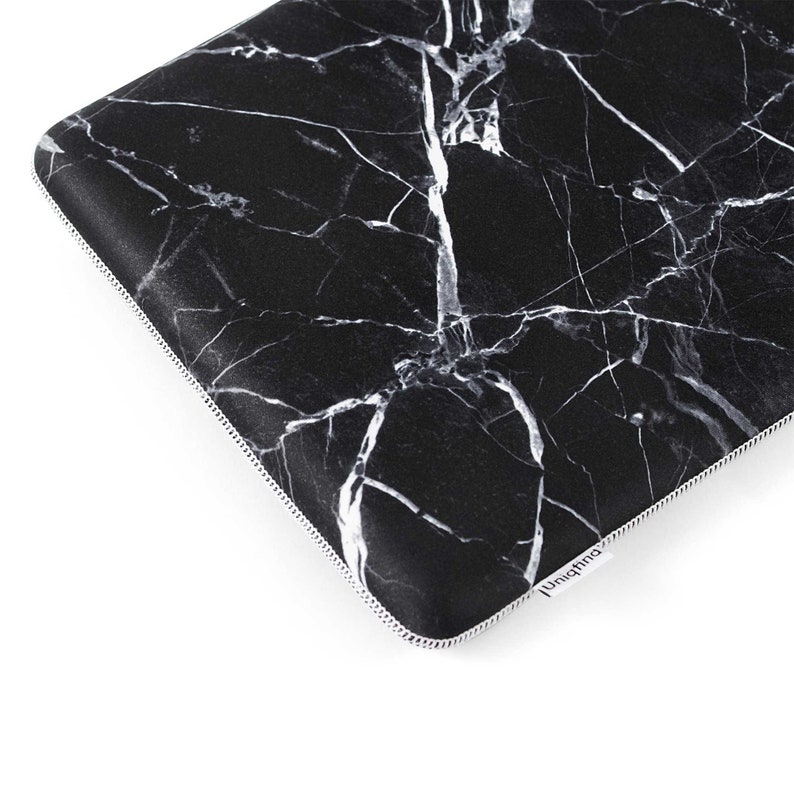 Puede incluir: Funda para port&aacute;til negra con un patr&oacute;n de m&aacute;rmol blanco. La funda tiene una cremallera y una etiqueta blanca "Uniqfind" en la esquina inferior derecha.