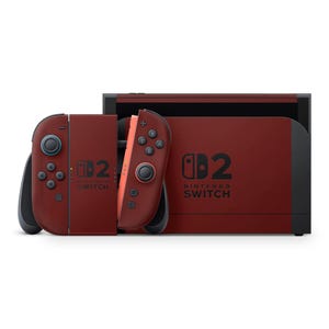 Può includere: Una console Nintendo Switch color amaranto con controller Joy-Con abbinati. La console e i controller presentano il logo Nintendo Switch. I controller sono staccati, mostrando il design e la disposizione dei pulsanti della console.