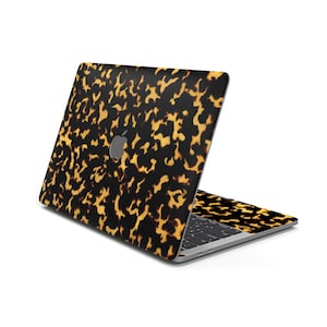 May include: A laptop computer with a tortoiseshell pattern on the lid and keyboard. The laptop is closed and the lid is facing the camera.