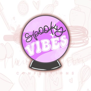 May include: A purple and white glass ball with the text "Spooky Vibes" in black lettering. The glass ball is on a black stand.