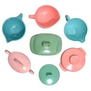 May include: A collection of seven kitchenware items including two turquoise pitchers, one pink bowl, one green rectangular lidded container, one pink oval lidded container, one pink round lidded container, and one green round lid, all in solid pastel colors.