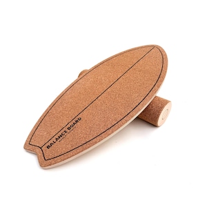 Könnte beinhalten: Ein Balance Board aus Kork in Surfbrettform mit einer zylindrischen Rolle. Das Board hat eine schwarze Umrandung und den Text "BALANCE BOARD" in Schwarz. Es ist für Gleichgewichtstraining und Übungen konzipiert.