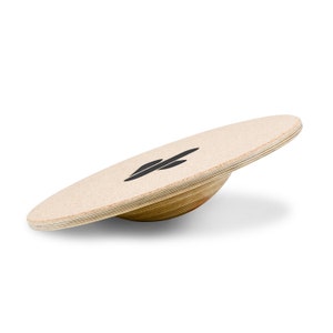 May include: A wooden balance board with a light brown, cork-like surface and a black logo. The board has a curved, layered wooden base. The product is designed for balance training and exercise.