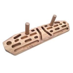 May include: A wooden climbing hold with a variety of shapes and sizes. The hold is made of natural wood and has a light brown color. There are two wooden pegs on the top of the hold.