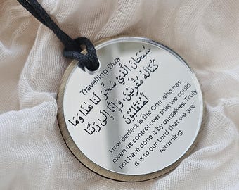 May include: A circular mirror pendant featuring the Travelling Dua in Arabic script and English translation. The text reads: How perfect is the One who has given us control over this; we could not have done it by ourselves. Truly it is to our Lord that we are returning. The pendant hangs from a black cord.