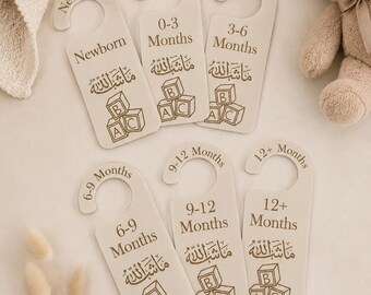 May include: A set of six cream-colored baby clothes dividers with arched tops, labeled "Newborn," "0-3 Months," "3-6 Months," "6-9 Months," "9-12 Months," and "12+ Months." Each divider features Arabic script and ABC blocks.