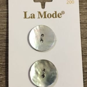 May include: Two white, round, mother-of-pearl buttons with a silver hook and eye closure. The buttons are labelled "La Mode" and "Hook 200".