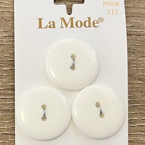 May include: Three white plastic buttons with two holes each. The buttons are on a white card with the text "La Mode" and "Hook 111" printed on it.