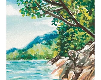 May include: Watercolor painting of a serene landscape featuring a turquoise lake, green mountains, and lush trees. The artwork includes a rocky shoreline and a blue sky with clouds. Signed by the artist, Lydia.