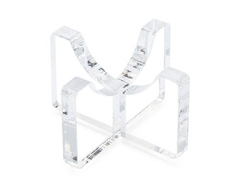 May include: A clear acrylic display stand for a small object, such as a crystal or figurine. The stand has a curved base and four legs.
