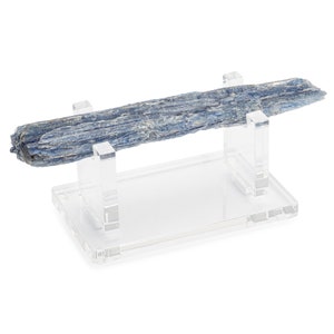 May include: A blue kyanite crystal specimen displayed on a clear acrylic stand. The crystal is long and thin with a striated surface.