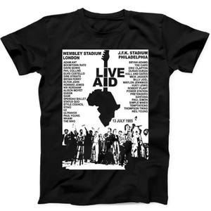 Puede incluir: Una camiseta negra de manga corta con un estampado gráfico blanco del cartel del concierto Live Aid del 13 de julio de 1985. El diseño incluye una lista de artistas del Wembley Stadium y J.F.K. Stadium, un mástil de guitarra y un mapa de África.