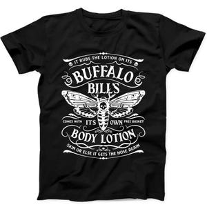 May include: Black t-shirt with a white graphic design. The design features the words "BUFFALO BILLS" above a moth illustration with a skull, and the text "IT RUBS THE LOTION ON ITS" and "BODY LOTION" with other text.
