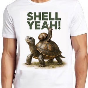 May include: White t-shirt with a humorous graphic of a tortoise carrying a snail. The text "SHELL YEAH!" is printed above the animals in green block letters. The design is centered on the shirt, suitable for casual wear.
