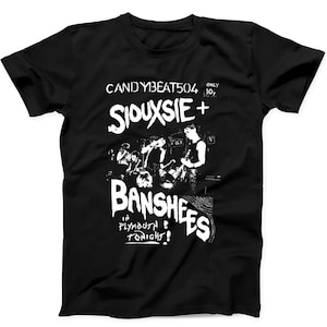 May include: A black short-sleeve t-shirt featuring a white graphic print of the band Siouxsie and the Banshees. The design includes the text CANDYBEAT504, ONLY 10p, SIOUXSIE + BANSHEES, and IN PLYMOUTH TONIGHT! with a concert scene illustration.