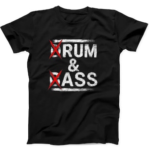 Op de afbeelding: Een zwart t-shirt met korte mouwen en de witte, verweerde tekst DRUM & BASS in het midden op de borst. De letters D en B zijn elk doorgestreept met een felrode X. Het ontwerp heeft een textuurrijk en versleten uiterlijk op de donkere stof.