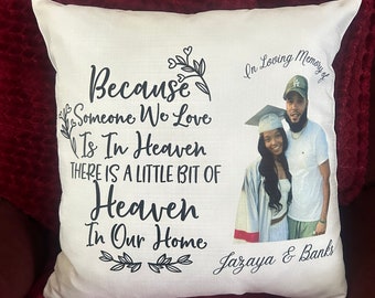 May include: A white pillow with a black floral design and the text "Because someone we love is in heaven there is a little bit of heaven in our home". The pillow also has a photo of a couple in graduation attire with the text "In loving memory of Jazaya & Banks".