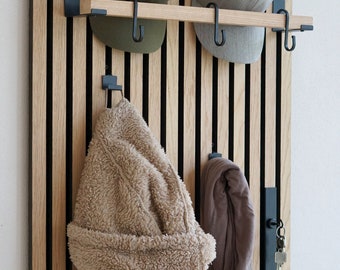May include: A wooden wall organizer with black metal hooks and a shelf. A brown fuzzy jacket, a brown scarf, and two hats are hanging on the hooks.