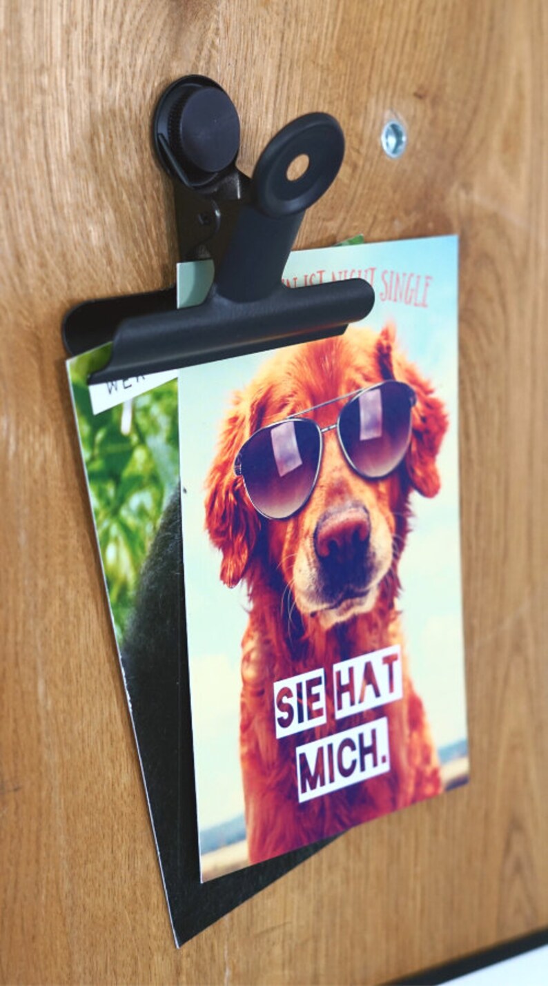 May include: A card featuring a golden retriever wearing sunglasses. The text on the card reads "Sie hat mich."