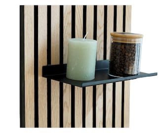May include: A black metal shelf with a green candle and a glass jar filled with coffee beans on a wood slat wall.