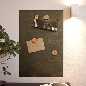 May include: A dark green slate board with four wooden round magnets holding business cards. The business cards are for "Salt + Vinegar" and "Les Naturals".