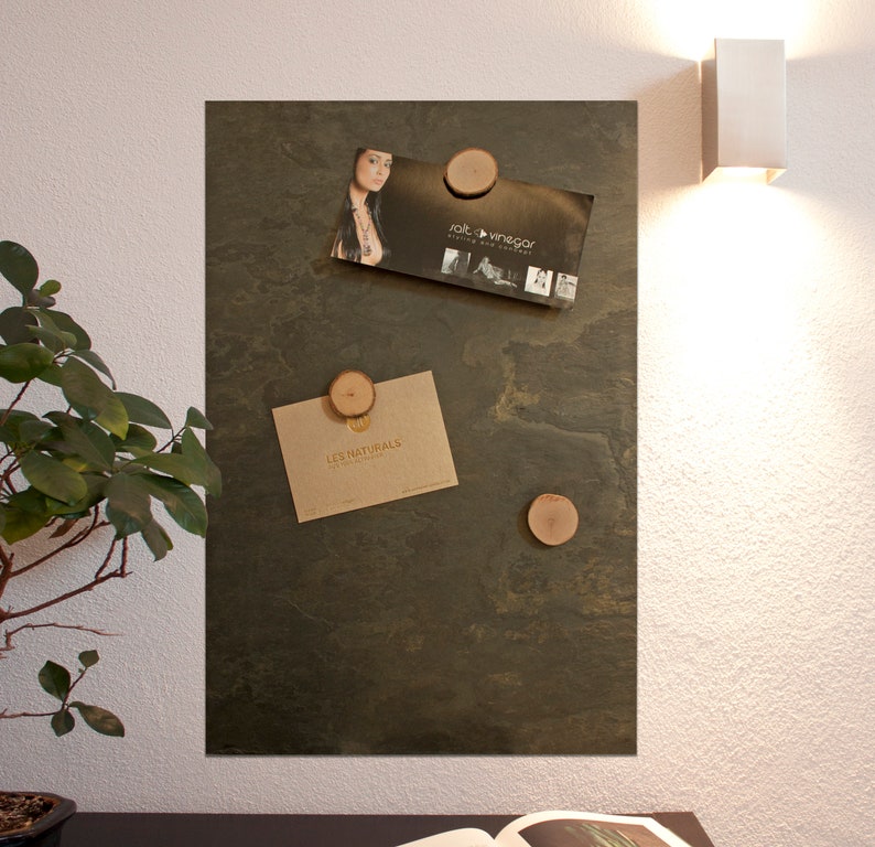 May include: A dark green slate board with four wooden round magnets holding business cards. The business cards are for "Salt + Vinegar" and "Les Naturals".