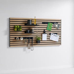 Könnte beinhalten: Ein Wandorganizer aus Holzlatten mit schwarzen Akzenten. Er verfügt über Regale, Haken und verschiedene Küchenutensilien und Zubehör, darunter eine kleine Pflanze, Gläser und Besteck. Der Organizer ist an einer weißen Wand montiert und bietet eine funktionale und stilvolle Aufbewahrungslösung.