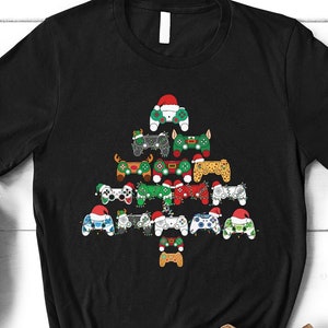 May include: Black t-shirt featuring a Christmas tree design made up of video game controllers. The controllers are decorated with Christmas colours and baubles.